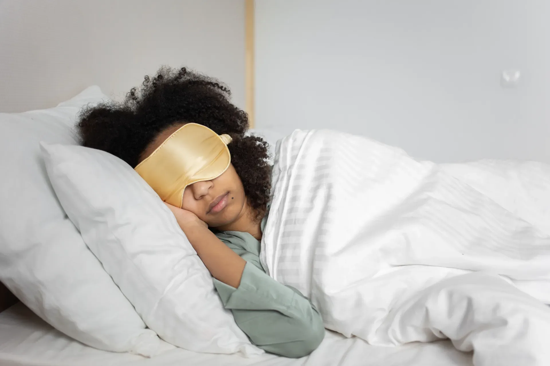 Man sleeping peacefully in bed with a soft glow from a bedside sound machine