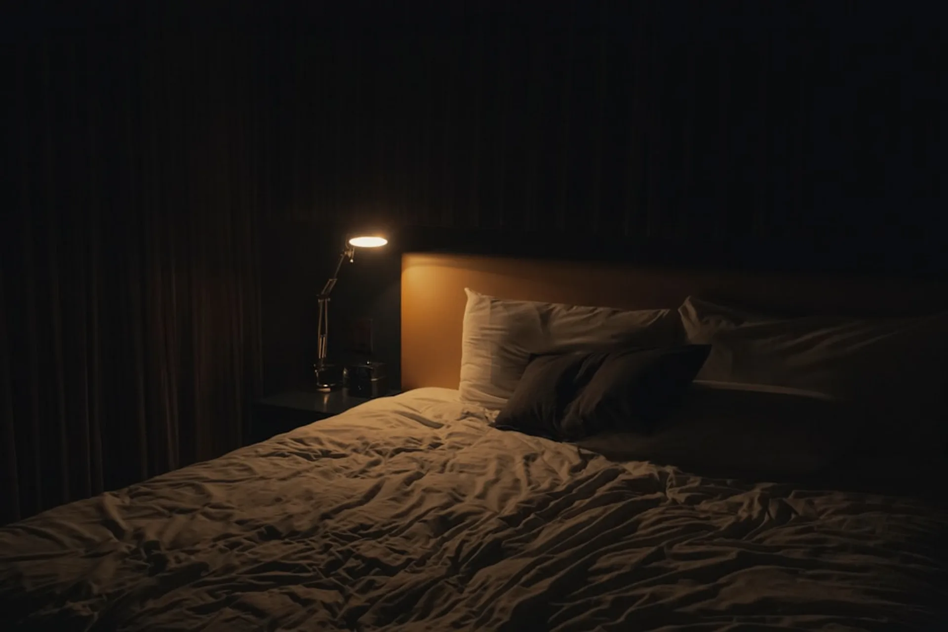 Cozy bedroom at night with soft lighting and a laptop playing audio therapy