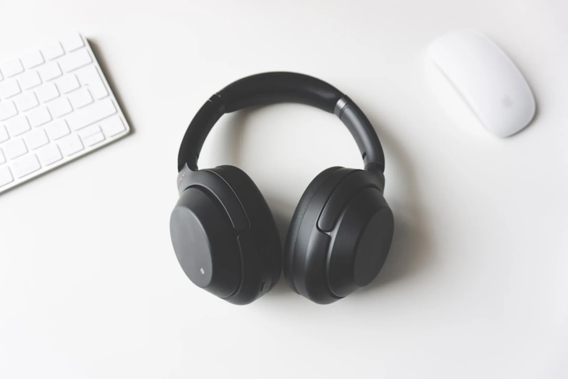Person wearing headphones working at a desk in an open office with soft ambient lighting
